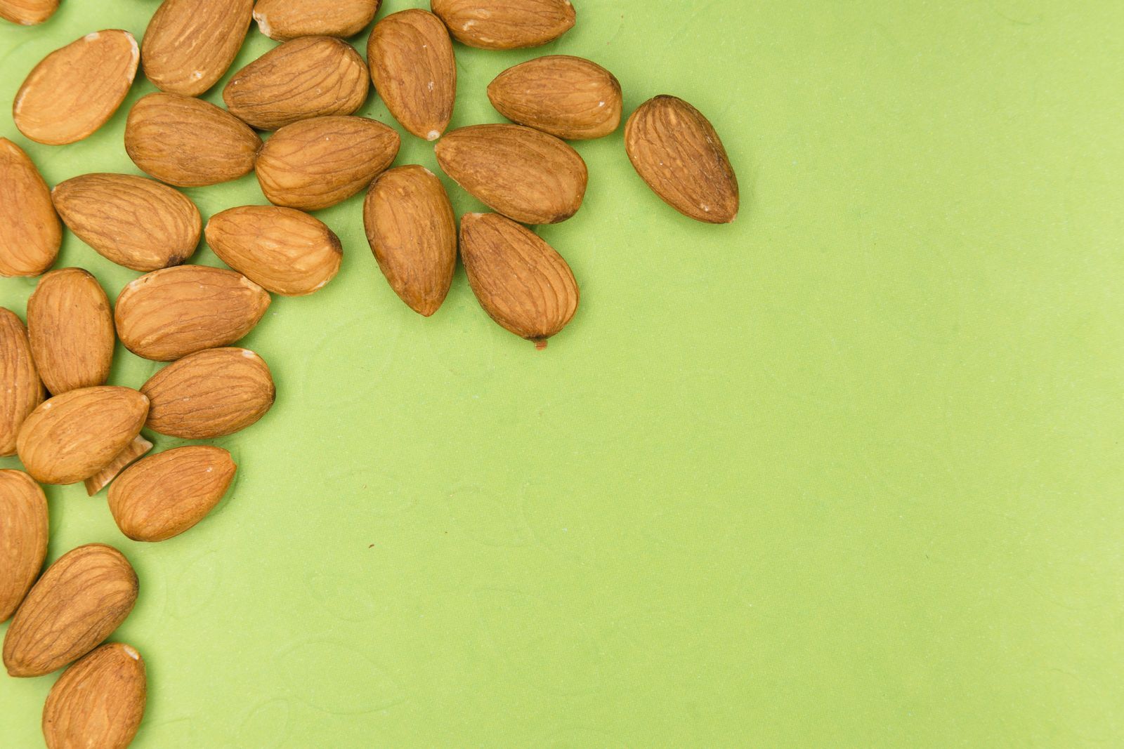 What Does Almond Smell Like? Almond nuts on a green surface