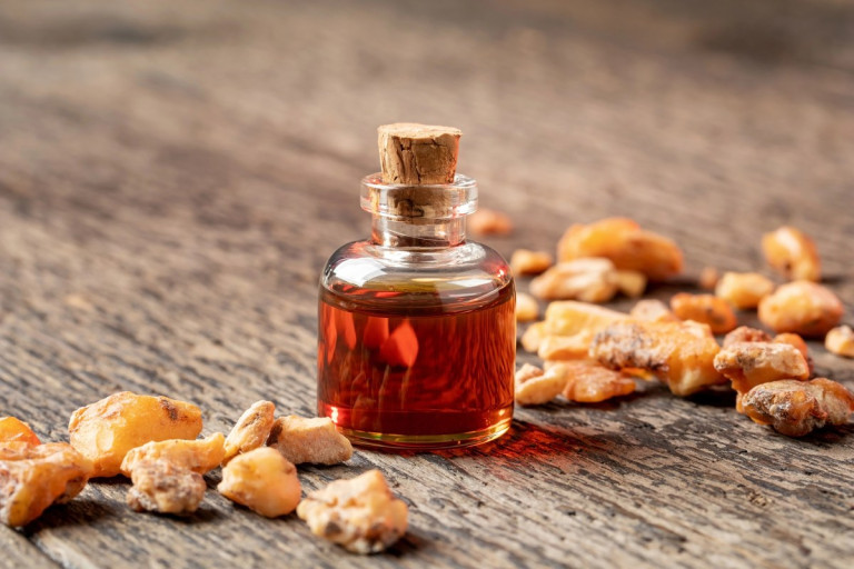 Golden Styrax benzoin resin with a bottle of benzoin essential oil on wood
