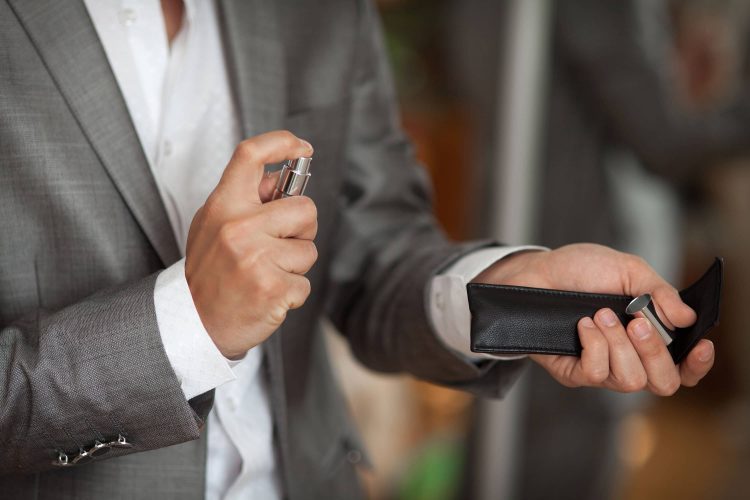 15 Best Colognes for Work and the Office man in gray suit spraying cologne