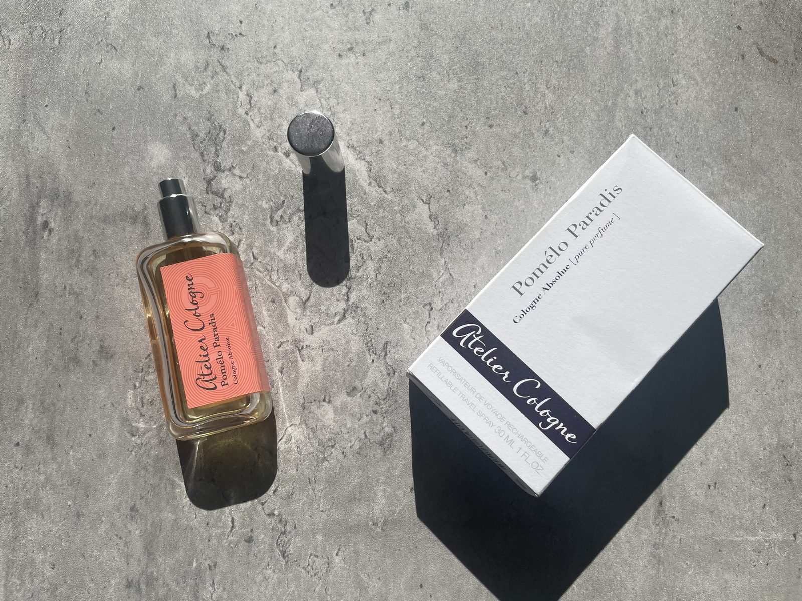 Atelier Cologne Pomelo Paradis Review: The Grapefruit That Stays Atelier Cologne Pomelo Paradis Cologne Absolue 30ml bottle, cap and box laid out on sunlit concrete