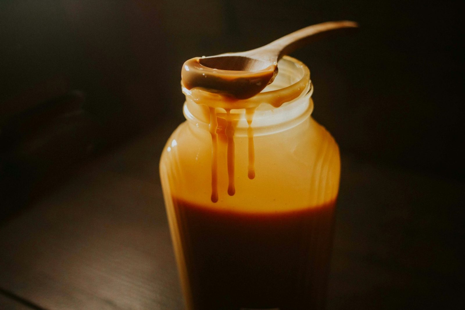 What Does Caramel Smell Like? Golden caramel dripping from a dipper into a glass jar