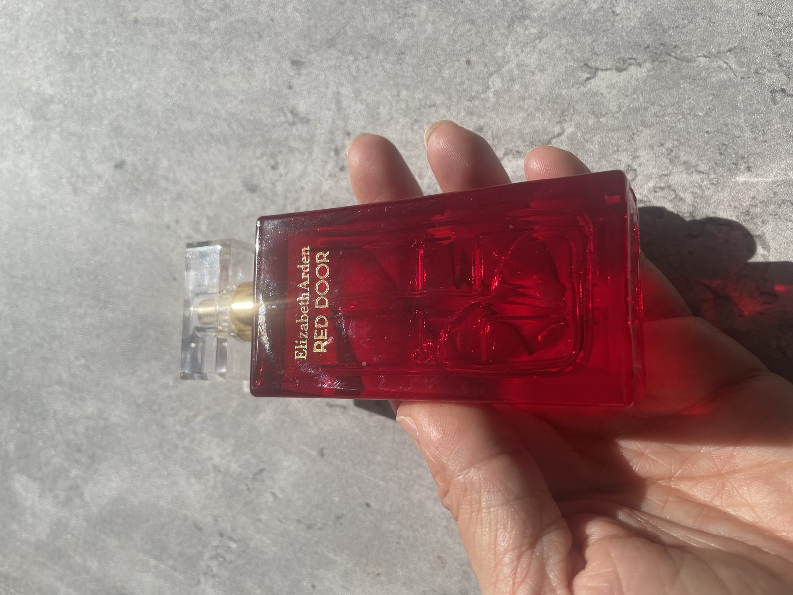 Elizabeth Arden’s Red Door Perfume Review: An Ageless Classic? Holding the Elizabeth Arden Red Door bottle with the gold Elizabeth Arden RED DOOR lettering facing camera
