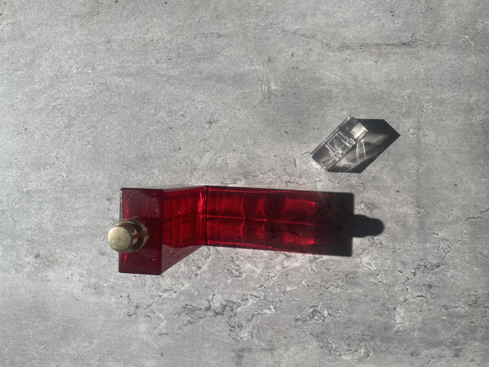 Elizabeth Arden’s Red Door Perfume Review: An Ageless Classic? Elizabeth Arden Red Door bottle on concrete casting a deep red shadow