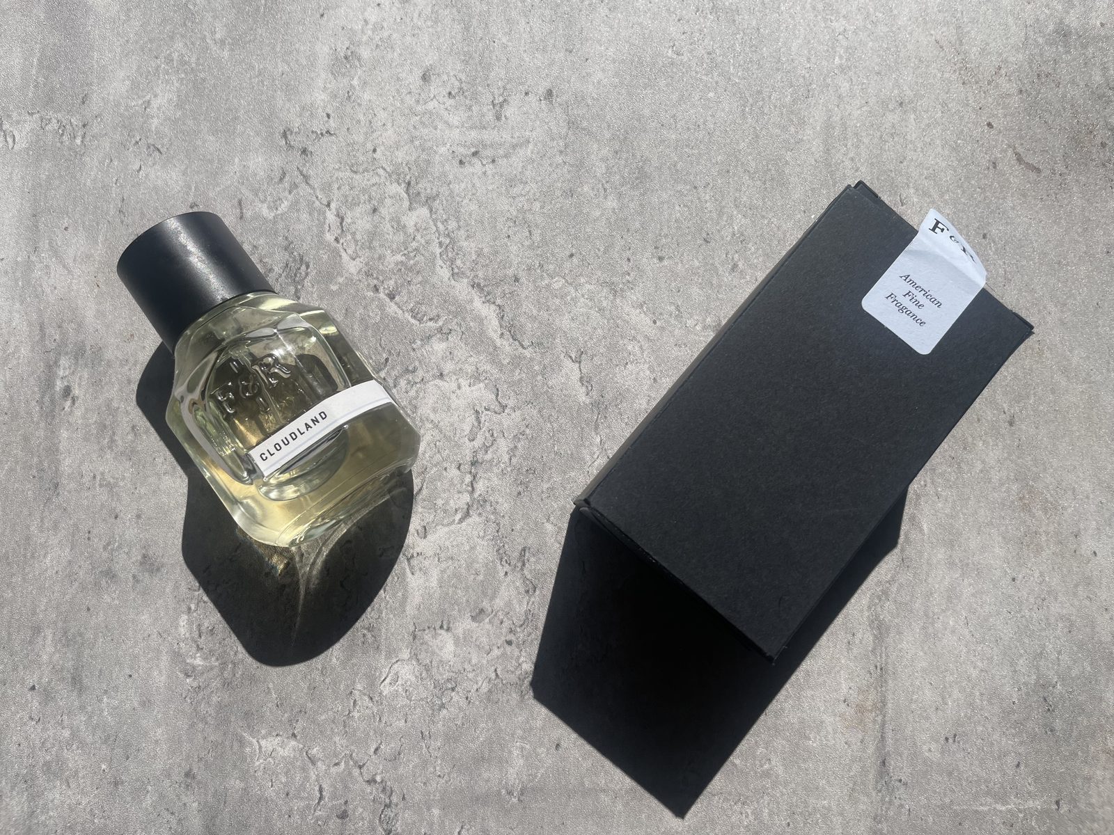 Fulton & Roark Cloudland Review: An Extrait That Won't Call Itself One Fulton & Roark Cloudland 50ml bottle beside its black F&R box on sunlit concrete, American Fine Fragrance seal visible