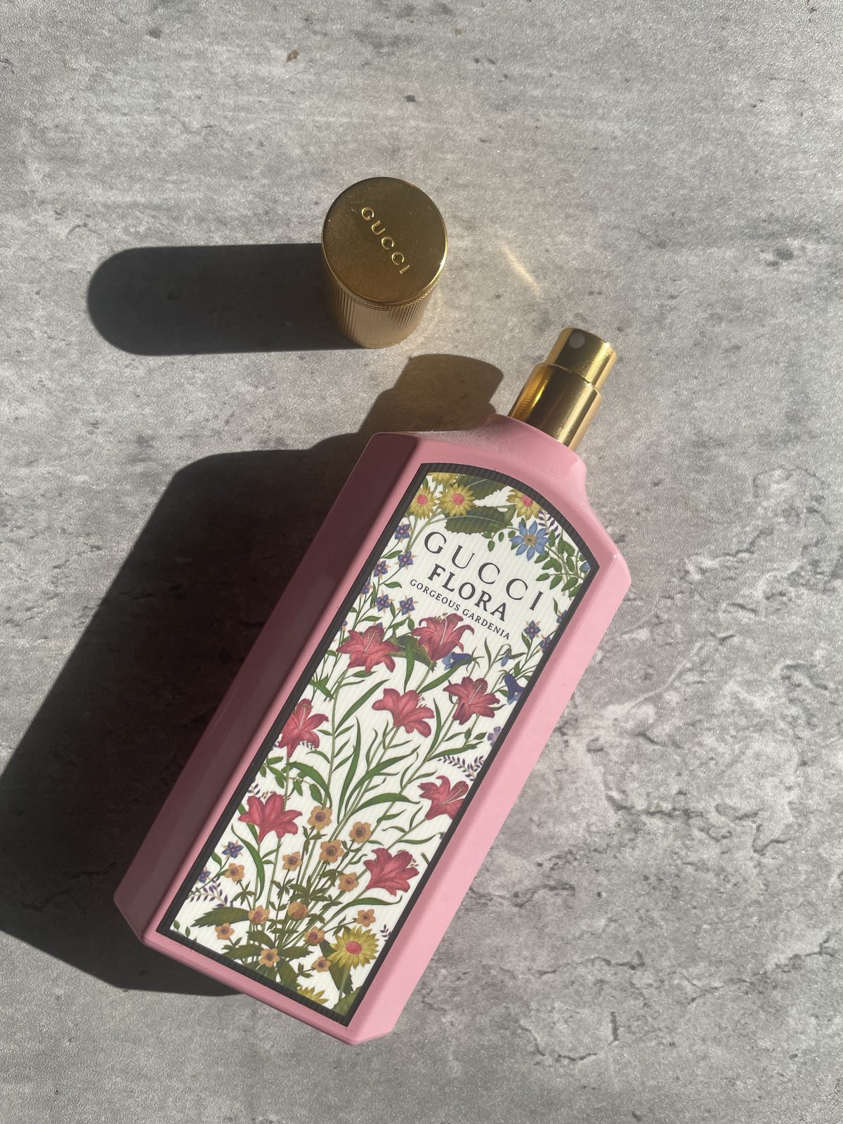 Gucci Flora Gorgeous Gardenia Review: The Flower That Isn't There Gucci Flora Gorgeous Gardenia bottle on concrete with the full chinoiserie print visible