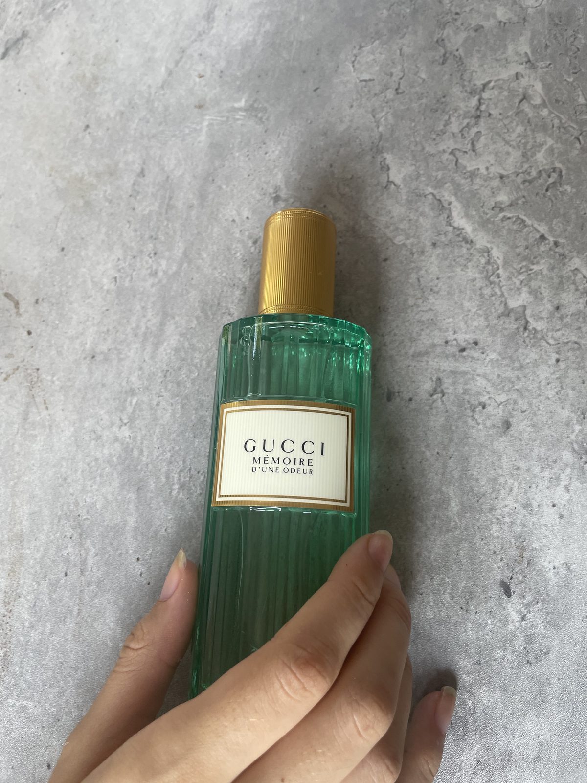 Gucci Memoire d’une Odeur EDP Review: Soothing & Soft Gucci Memoire d’une Odeur EDP 100 ml bottle held against a concrete background