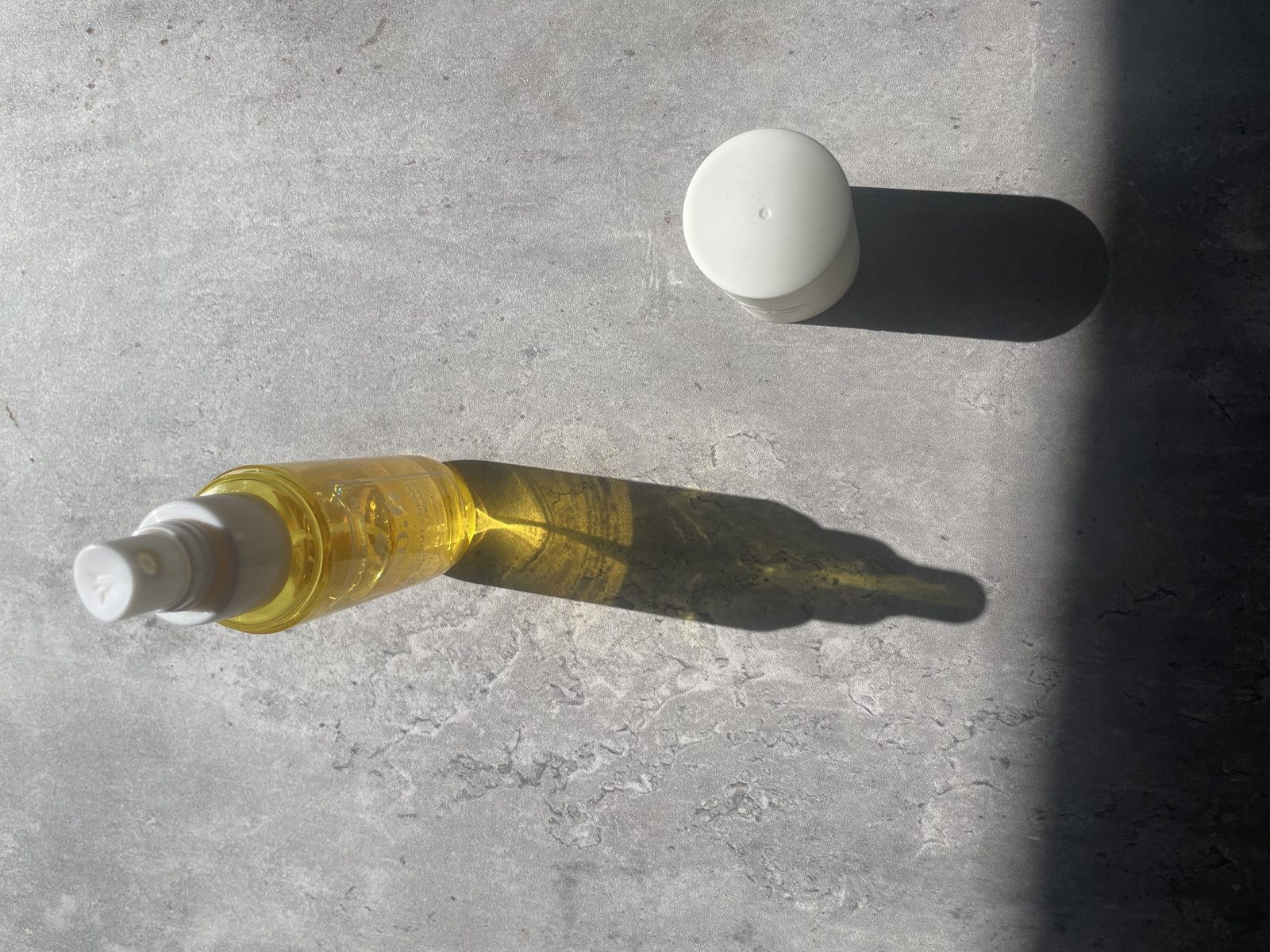 MCoBeauty No.6 Coconut Cream Review: The Batch Code Its Sibling Hides MCoBeauty No.6 Coconut Cream & White Florals fragrance mist lying on sunlit concrete beside its white cap