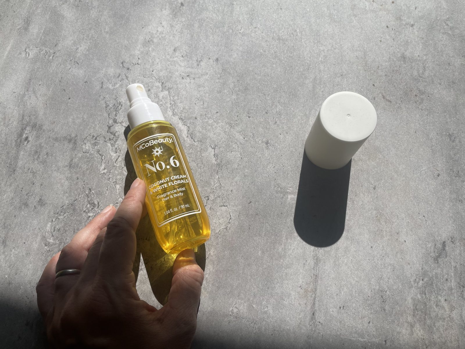MCoBeauty No.6 Coconut Cream Review: The Batch Code Its Sibling Hides MCoBeauty No.6 held above concrete with the yellow juice casting a coloured shadow