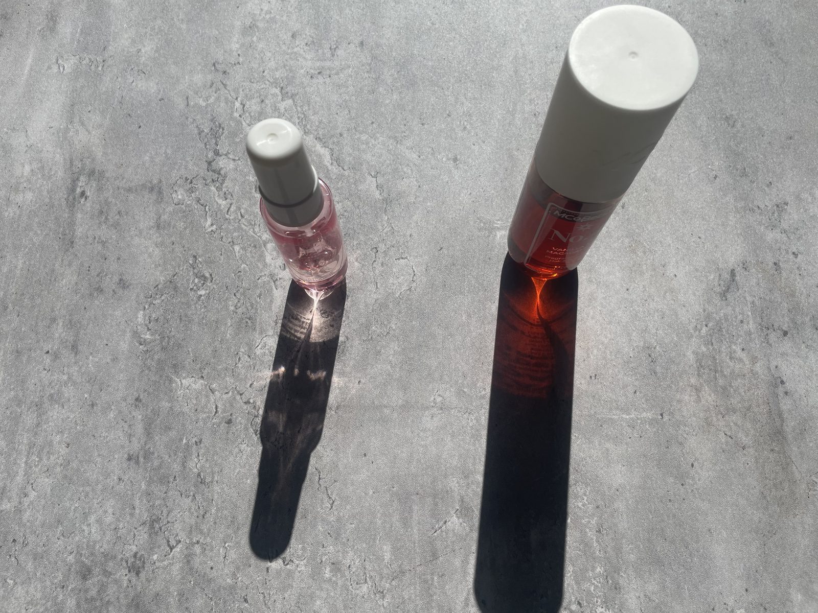 MCoBeauty vs Sol de Janeiro: I Own Both, and They Don't Smell Alike MCoBeauty No.4 and Sol de Janeiro Cheirosa 68 standing upright on concrete, each casting a long coloured shadow