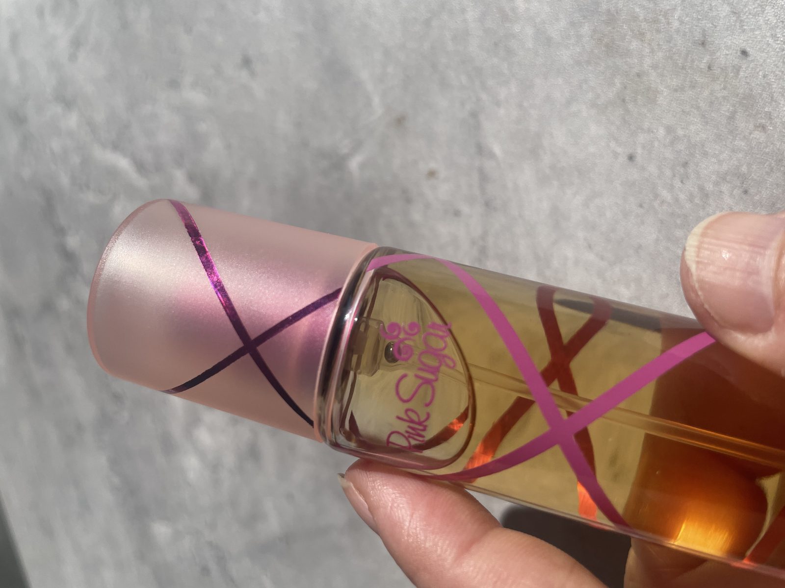 Pink Sugar Perfume Reviewed: Incredibly Sweet Close-up of the Pink Sugar logo and frosted pink cap with its magenta ribbon stripe