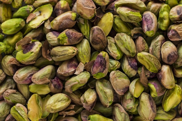 Shelled pistachio kernels in close-up, showing the green that separates pistachio from almond